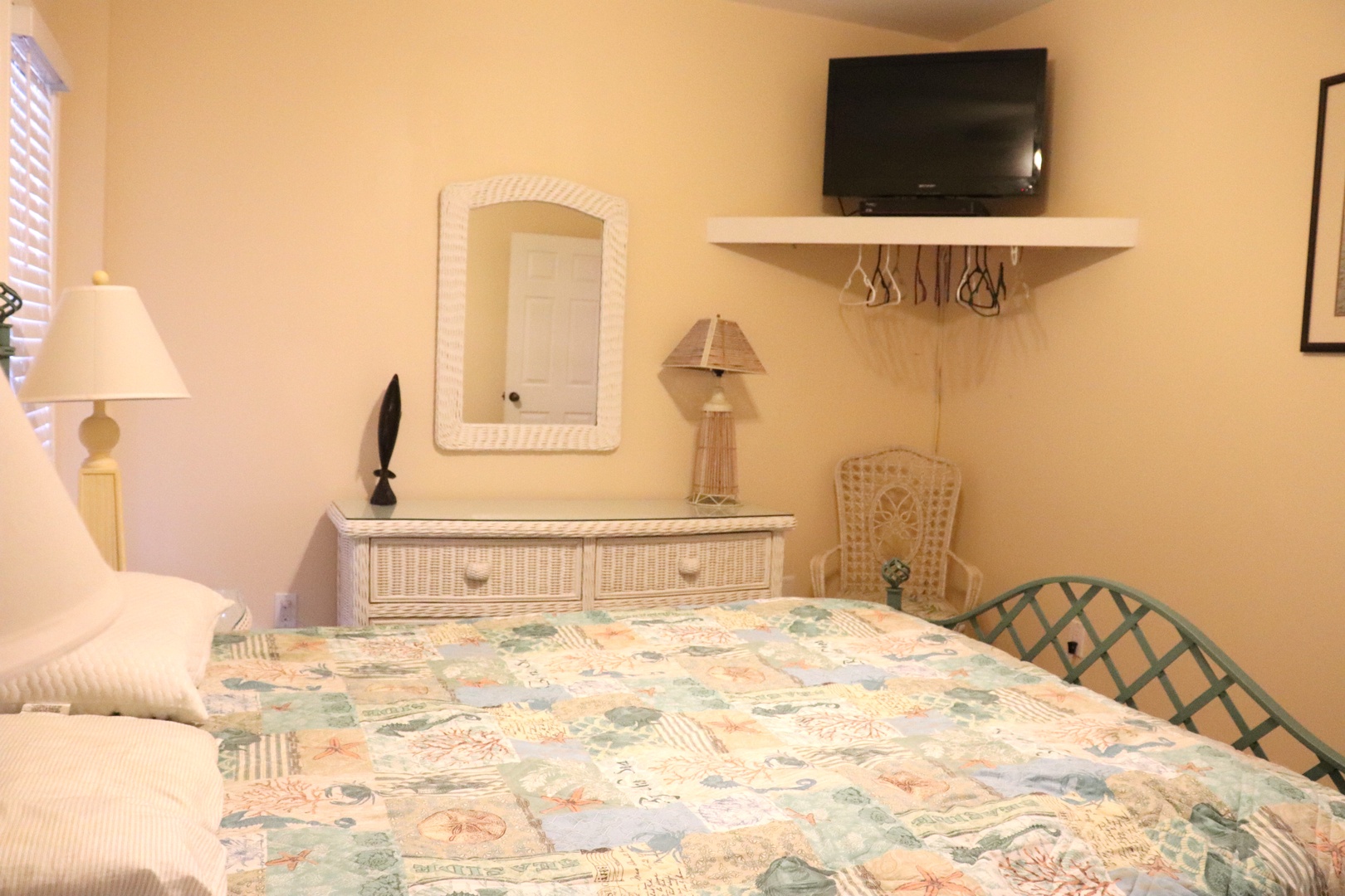 Your cozy bedroom features cheerful coastal bedding, wicker furnishings, and a wall-mounted TV for relaxing evenings after beach days.