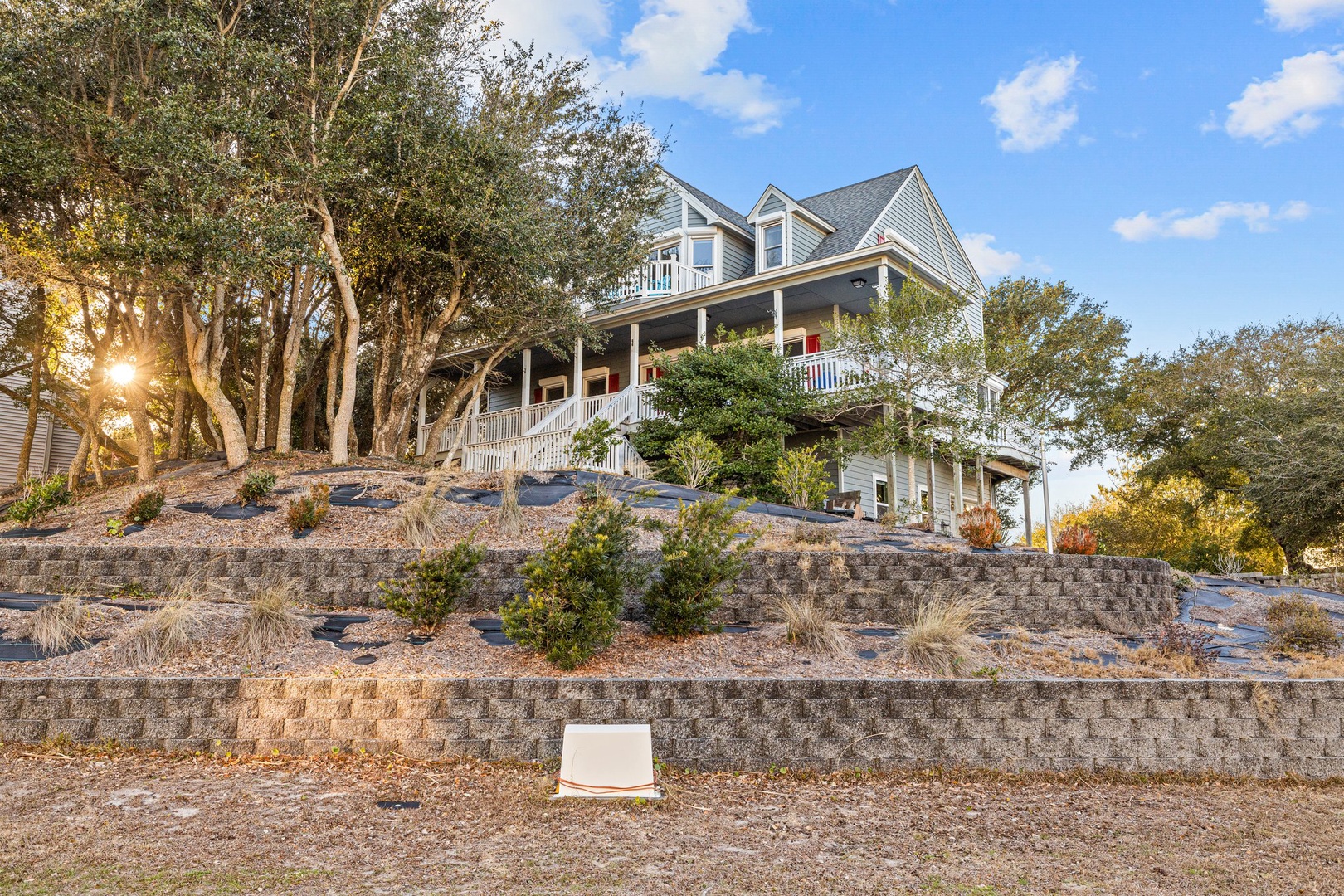 Impressive multi-story coastal home featuring wraparound porches and beautiful landscaped terraces set among mature oak trees.