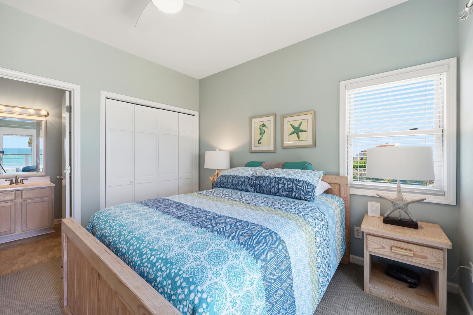 Your coastal retreat features soft ocean-inspired tones, a plush bed dressed in aqua linens, and a peaceful view that brings the sea breeze right to your window.