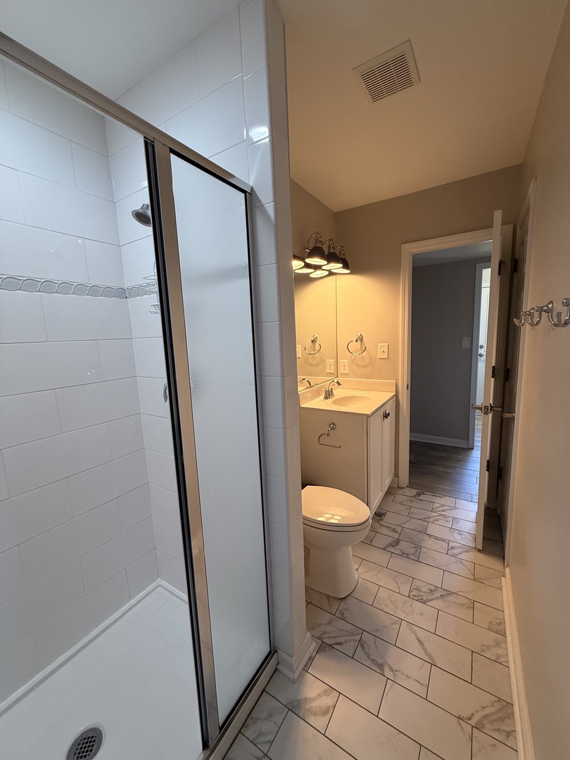 Step into your private bathroom with modern fixtures and a spacious glass-enclosed shower. Crisp white tiles and fresh towels await your arrival.