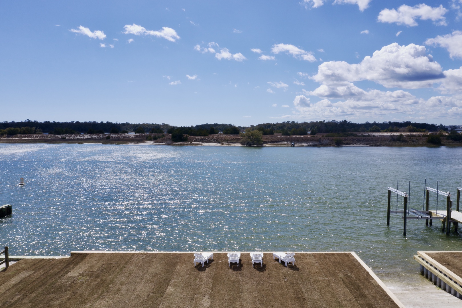Waterfront deck with lounge chairs overlooking sparkling lake and private dock access.