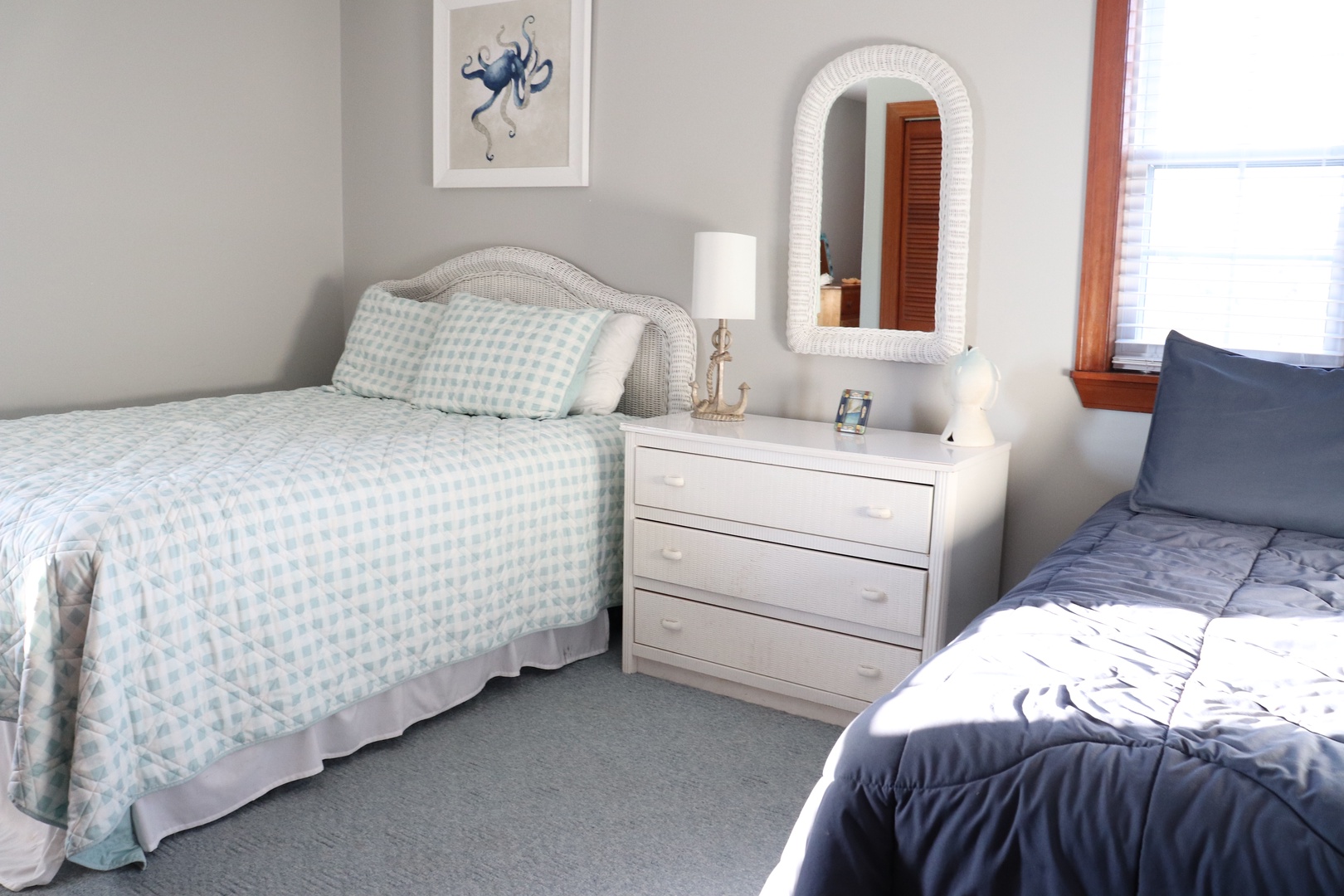 Two comfortable beds await in your peaceful bedroom retreat, featuring coastal decor and natural light streaming through your window.