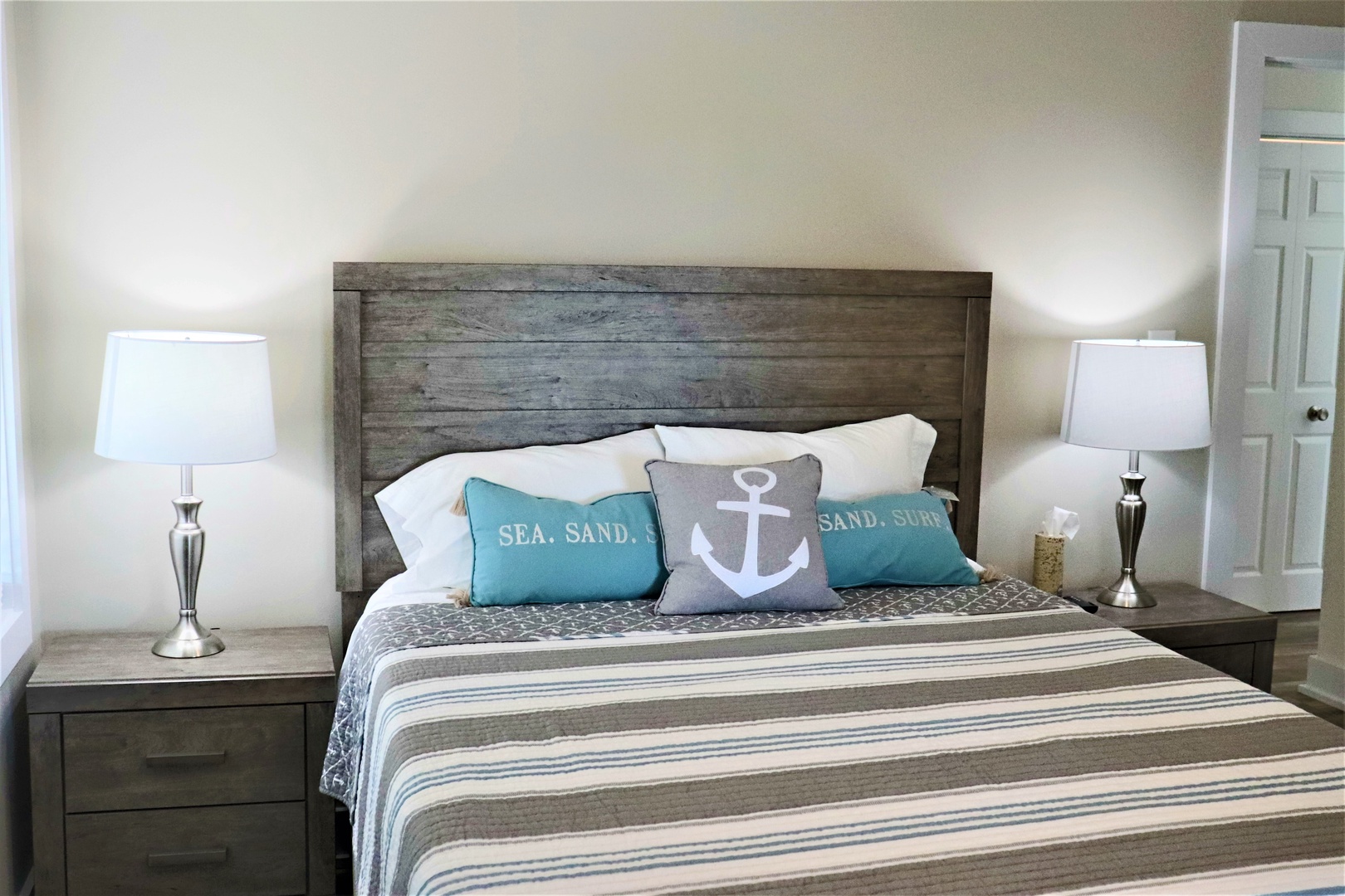 Drift off in your coastal-themed bedroom featuring weathered wood headboard, nautical pillows, and matching bedside lamps for perfect seaside vibes.