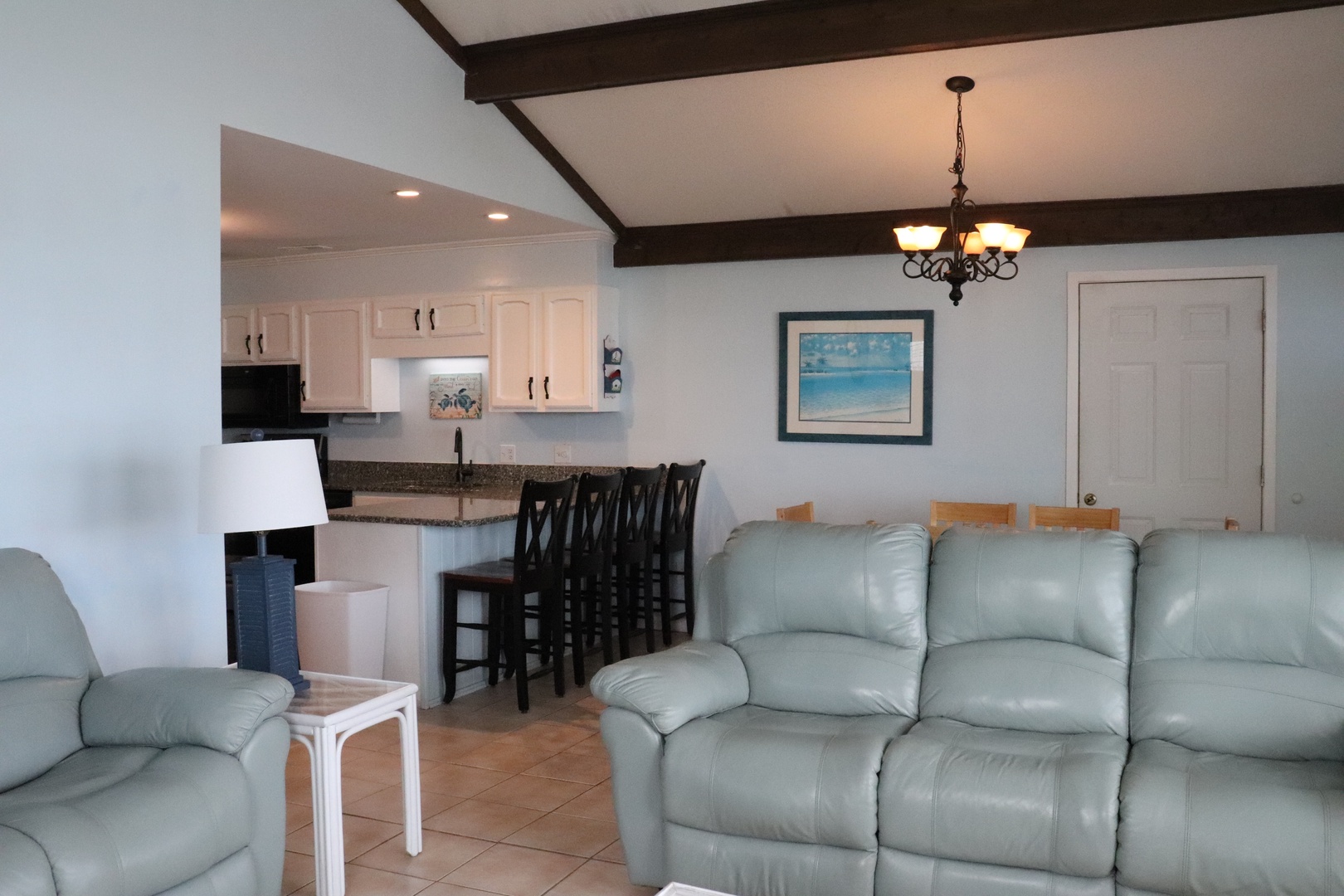 Stretch out on plush leather recliners and feel at home in this airy, open-concept living space. The full kitchen and breakfast bar invite lazy mornings, while warm beams overhead add coastal charm.