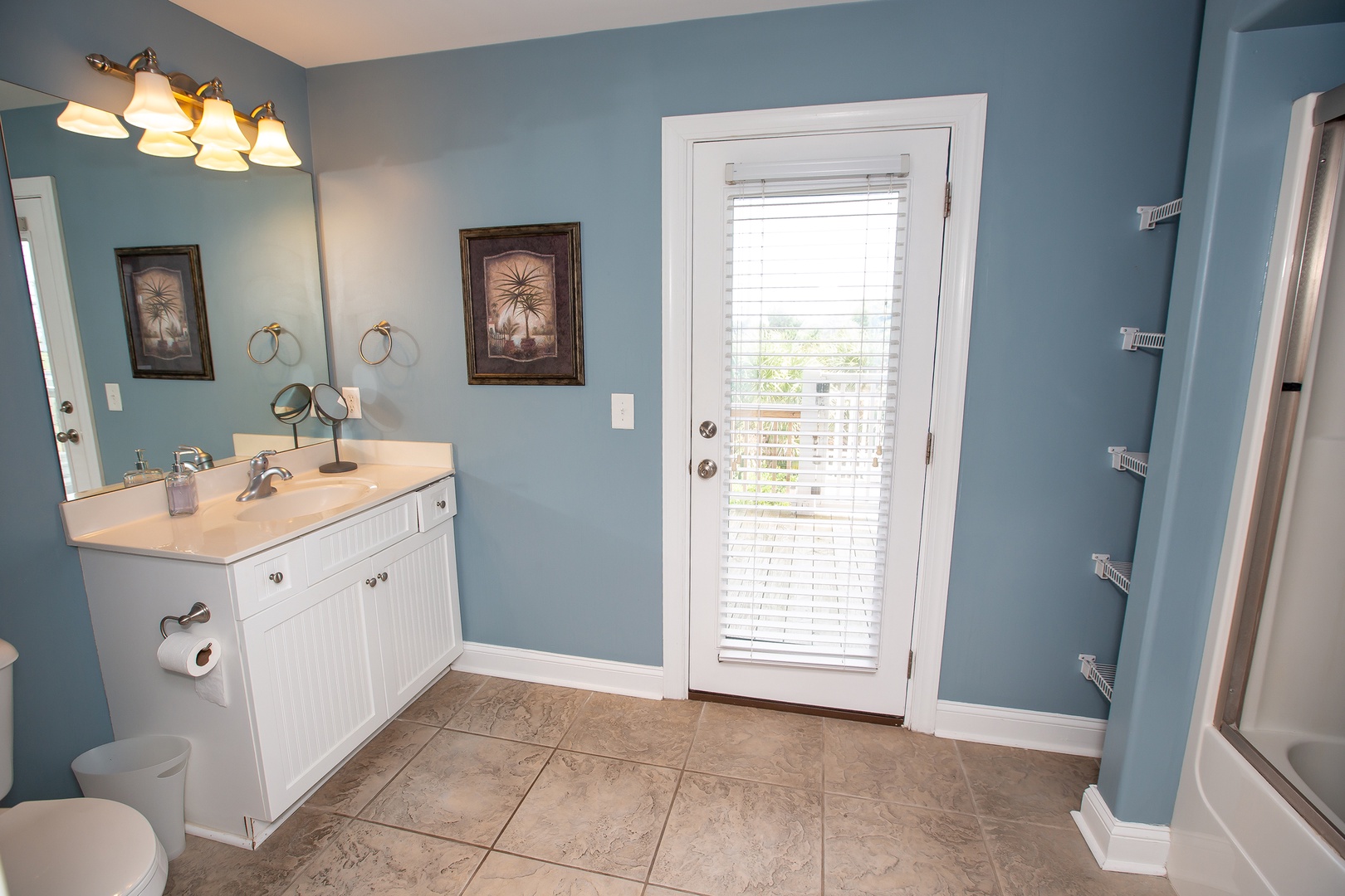 Your spacious bathroom features coastal-inspired blue walls, elegant fixtures, and a private door leading to your outdoor space.