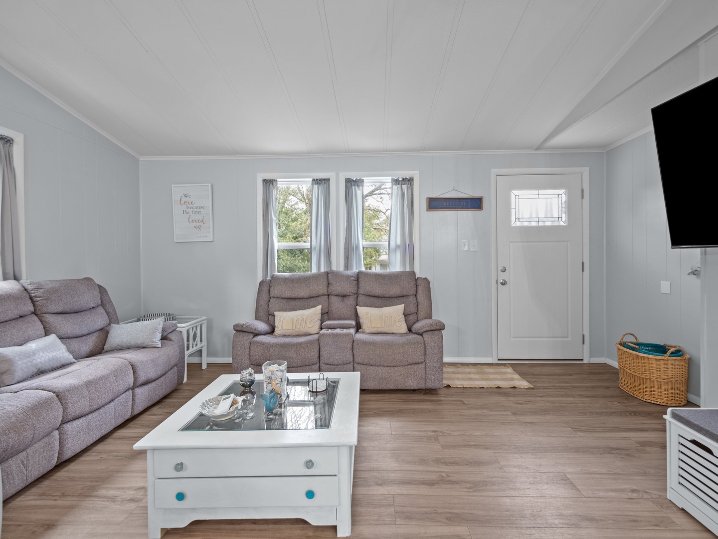 Sink into plush recliners in your bright living space, where charming coastal decor and warm wood floors create the perfect spot to unwind.