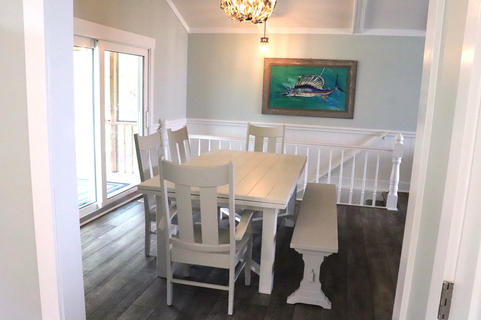 Gather around your elegant dining table for memorable meals with coastal charm and natural light streaming through French doors.