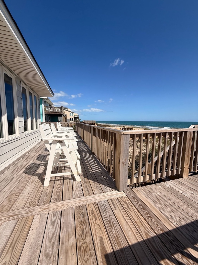Your expansive wooden deck stretches toward the sparkling turquoise waters, lined with Adirondack chairs perfect for soaking up endless ocean breezes and sunshine.