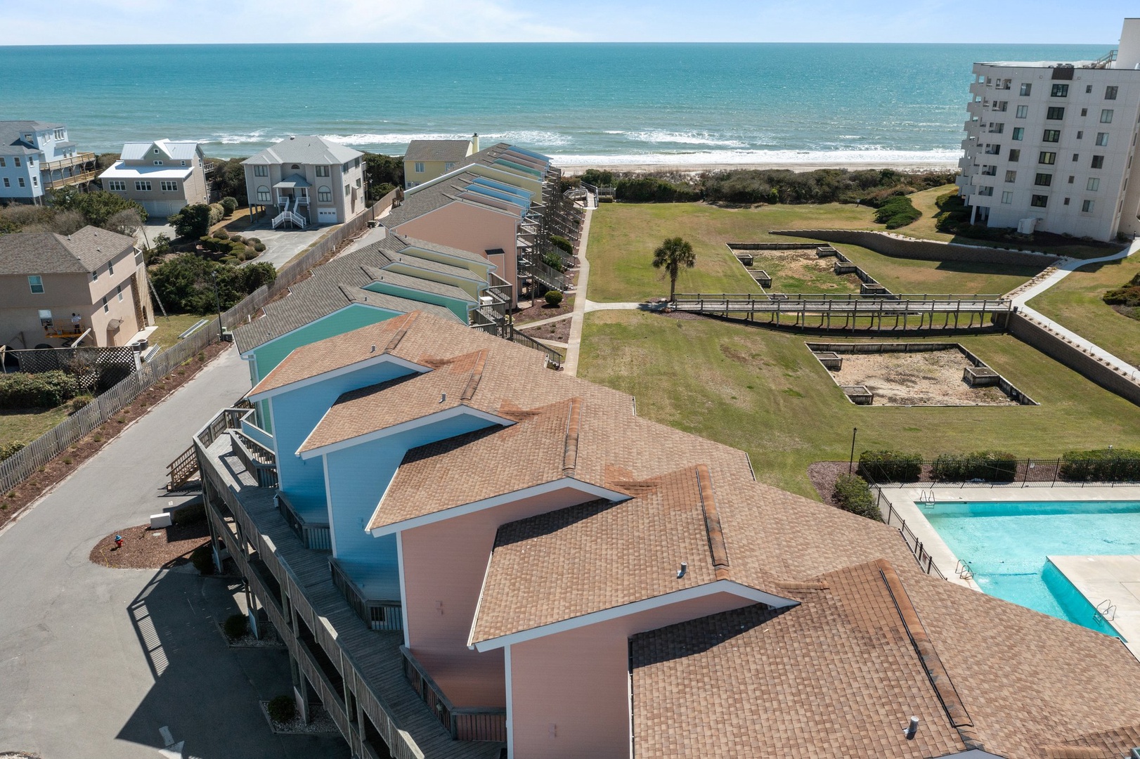 Beachfront property complex featuring swimming pool and direct ocean access with scenic coastal surroundings.