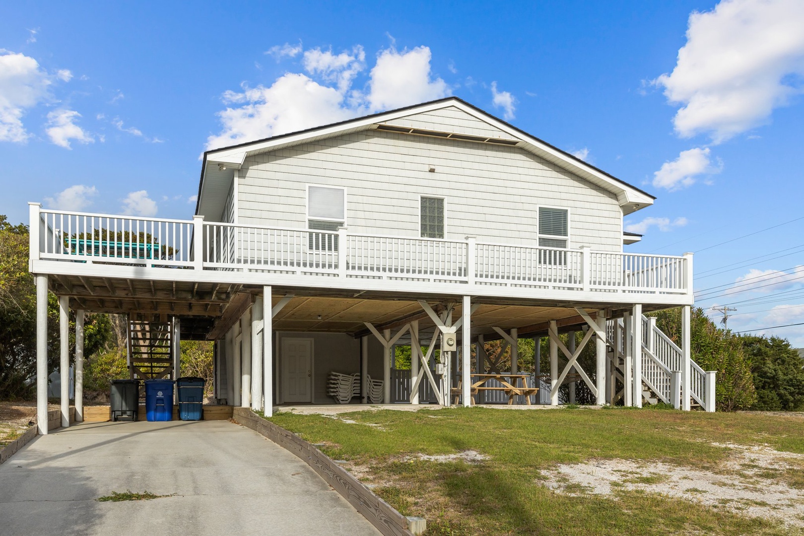 Elevated beach house with wraparound deck and ground-level parking provides coastal charm and convenient access.
