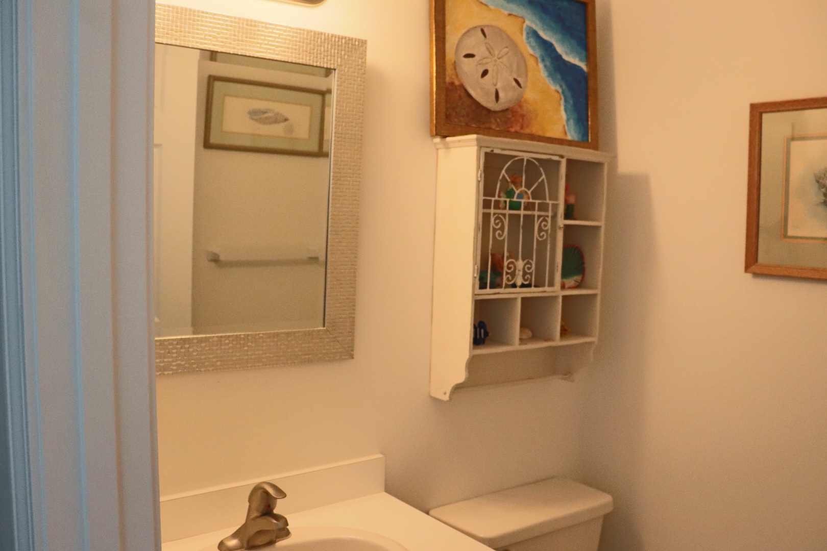 Your bathroom features coastal charm with seashell decor, practical storage, and beachy artwork to start your day refreshed.