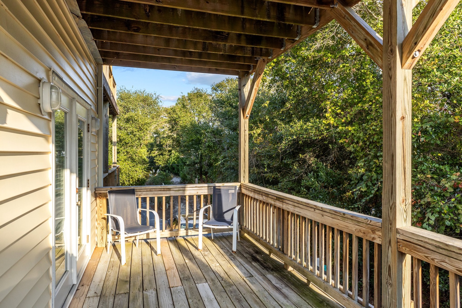 Enjoy your morning coffee on this peaceful covered deck surrounded by lush greenery and natural light.