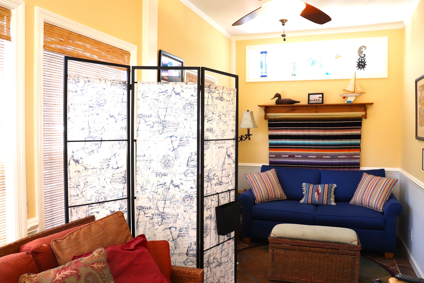Relax in your colorful living room with a bold blue sofa, charming nautical screen divider, and warm yellow walls.