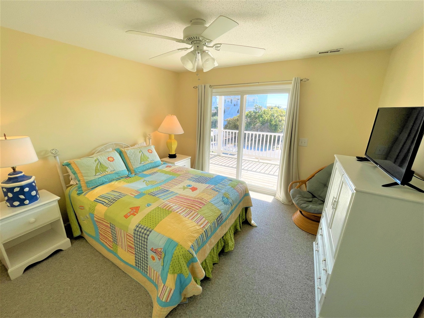 Drift off in this cheerful bedroom where colorful quilted bedding and gentle ceiling fan create your perfect retreat.