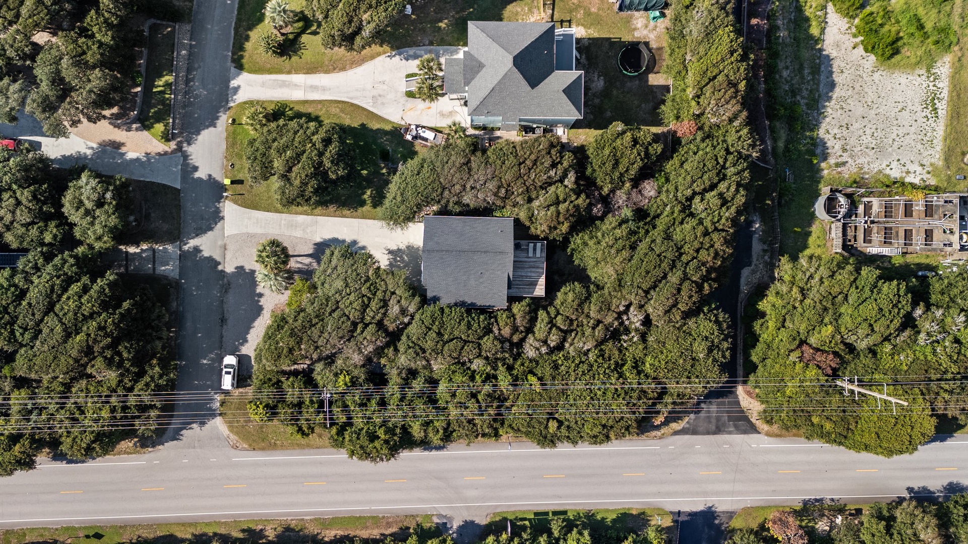 Aerial view of the property nestled among mature trees in a peaceful residential neighborhood with convenient street access.