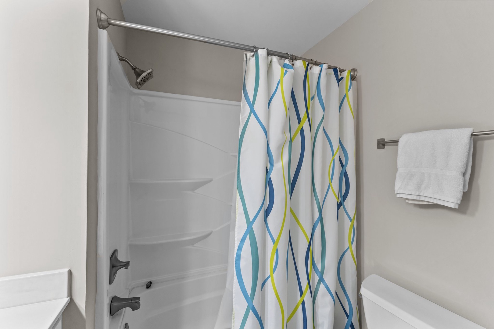Step into your private bathroom featuring a refreshing shower with modern curved design and fresh linens waiting for you.
