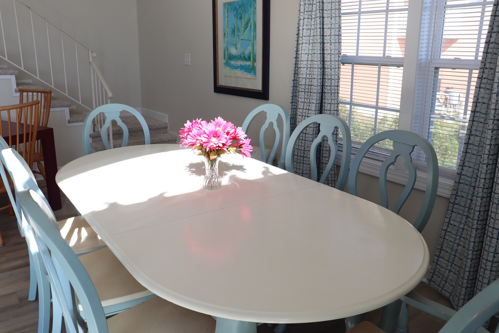 Gather around this sunny dining table for memorable meals with pink flowers brightening your mornings together.