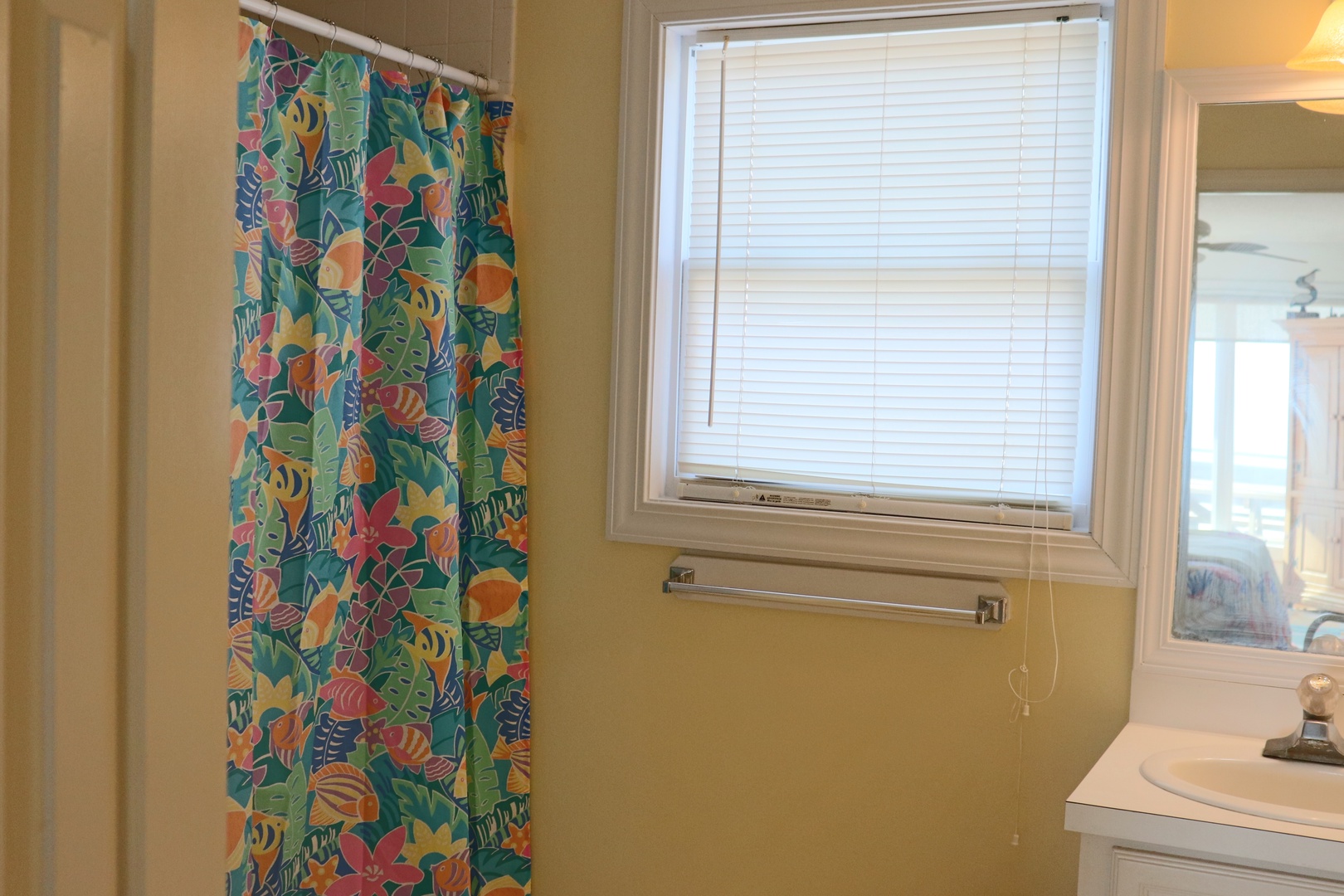 Your bright bathroom features a cheerful tropical shower curtain and natural light, creating a refreshing morning routine space.