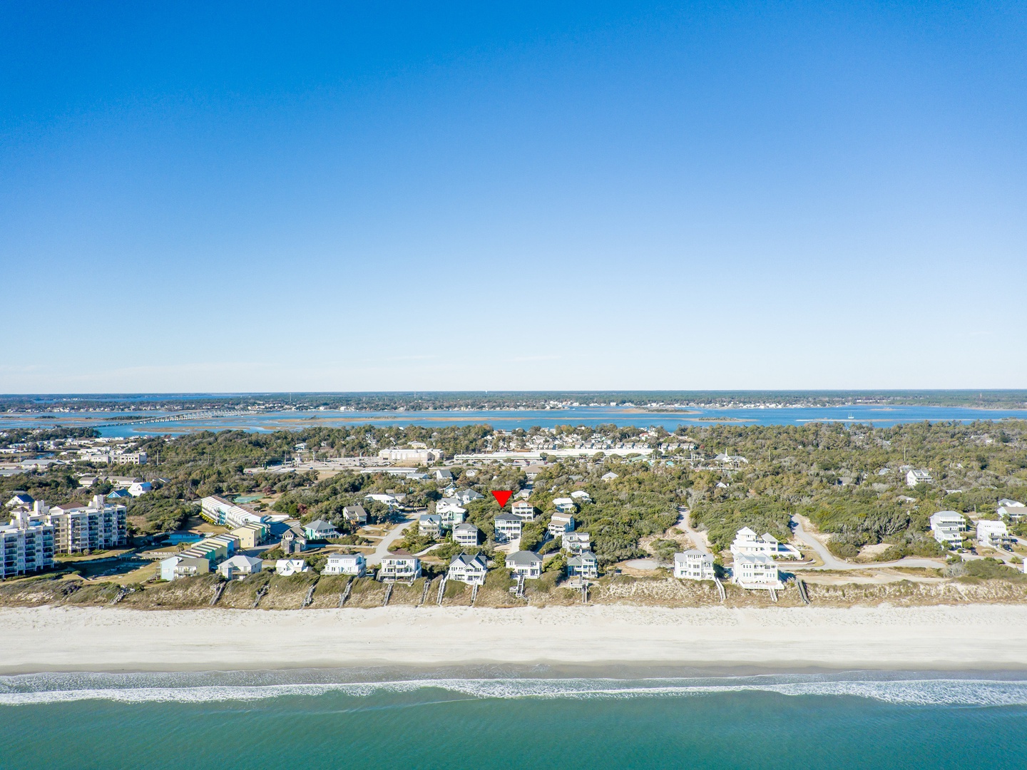 Aerial view showcases a stunning beachfront community with pristine sandy shores and turquoise waters stretching to the horizon.