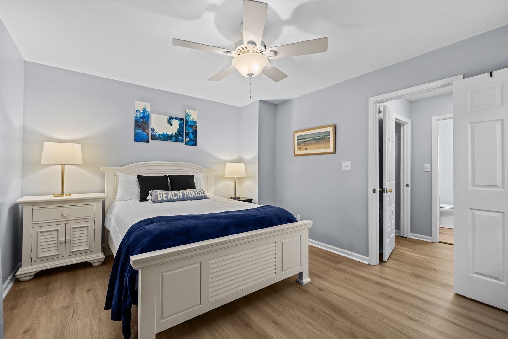 Rest peacefully in this coastal-themed bedroom with crisp white furniture, soothing blue accents, and gentle ceiling fan breezes.