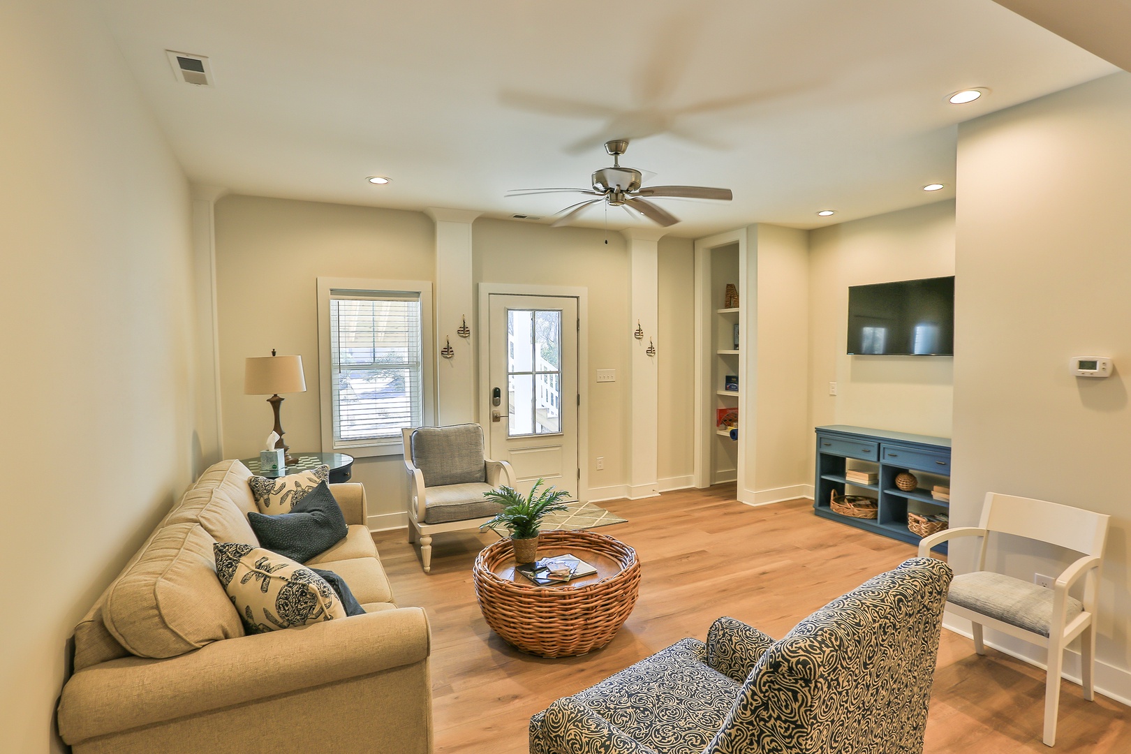 Settle into your spacious living room with comfortable seating, warm wood floors, and modern entertainment center perfect for relaxing evenings.