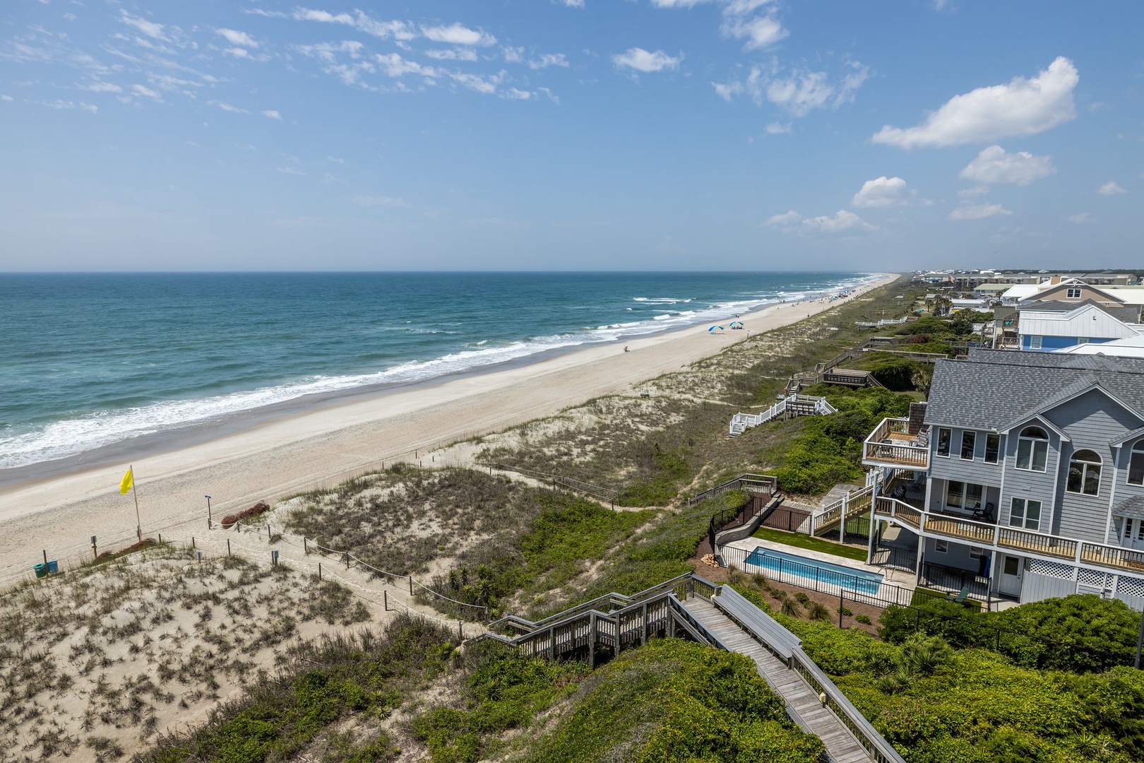 Stunning oceanfront property with private pool and direct beach access via wooden boardwalk through pristine dunes.