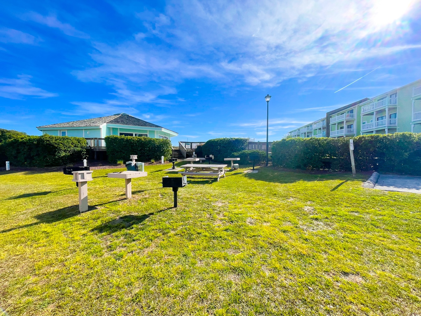 Coastal property featuring landscaped grounds with recreational amenities and neighboring accommodations under expansive blue skies.