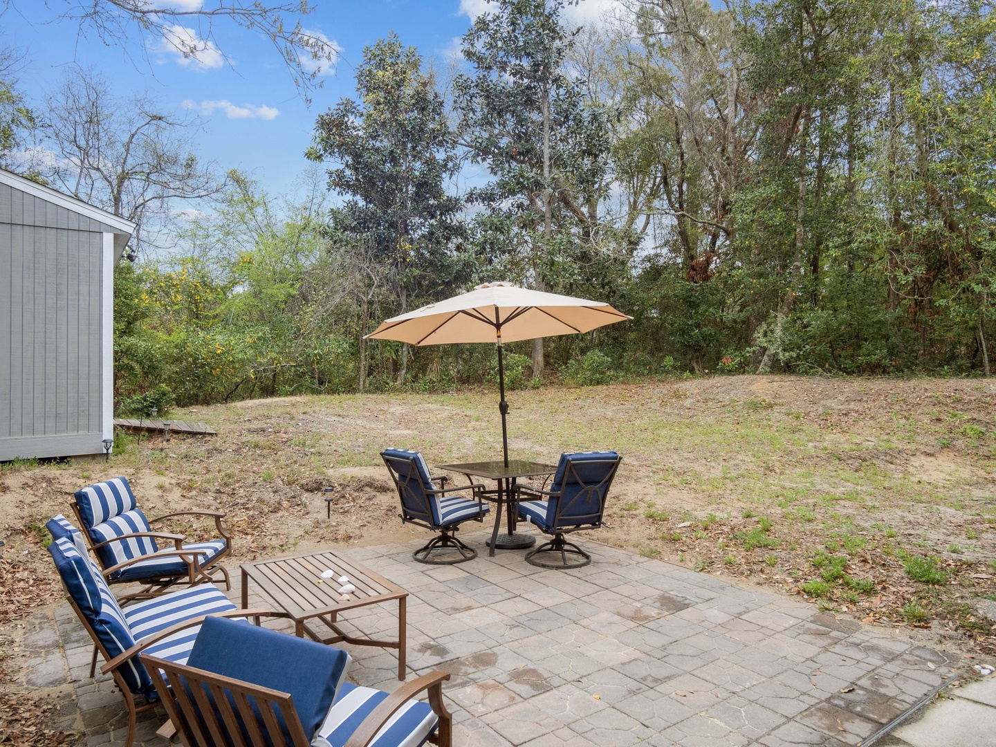 Relax on your private patio with comfortable seating, umbrella shade, and peaceful wooded surroundings for the perfect outdoor retreat.