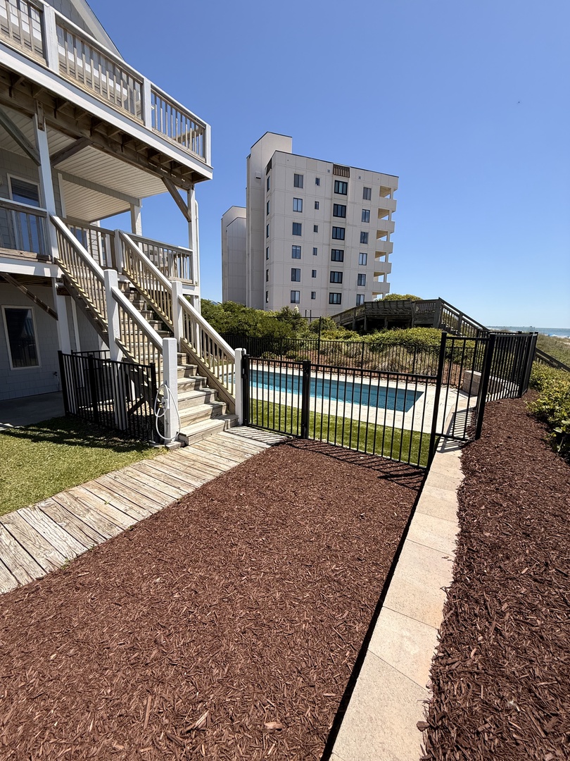 Modern multi-story property featuring sleek architecture with balconies overlooking a landscaped courtyard area framed by mulched grounds and greenery.