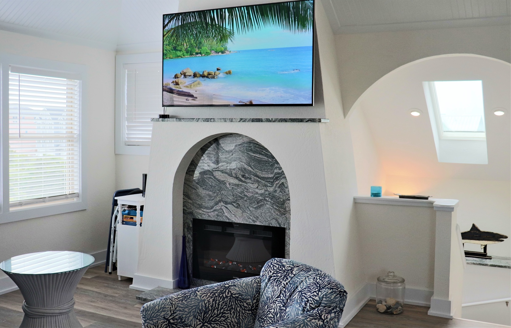 Unwind in your stylish living space featuring a cozy fireplace and large TV displaying tropical scenes—perfect for relaxing evenings.