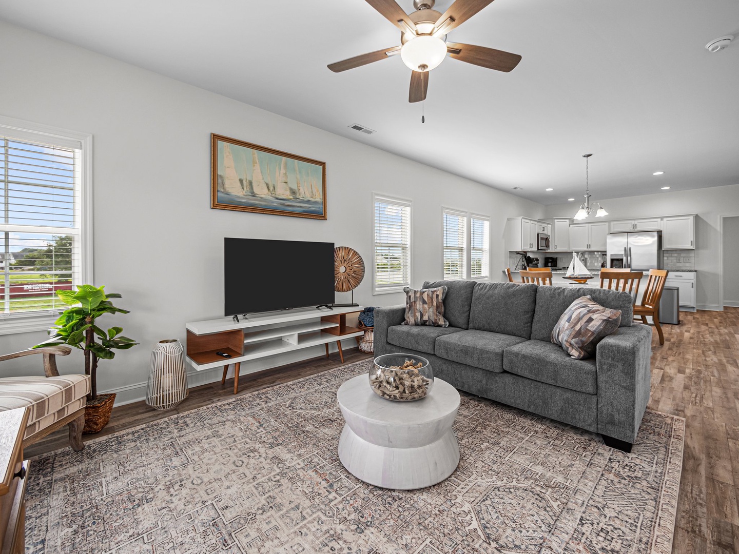 Sink into plush seating where modern comfort meets coastal charm, with your favorite shows on the big screen and kitchen moments just steps away.