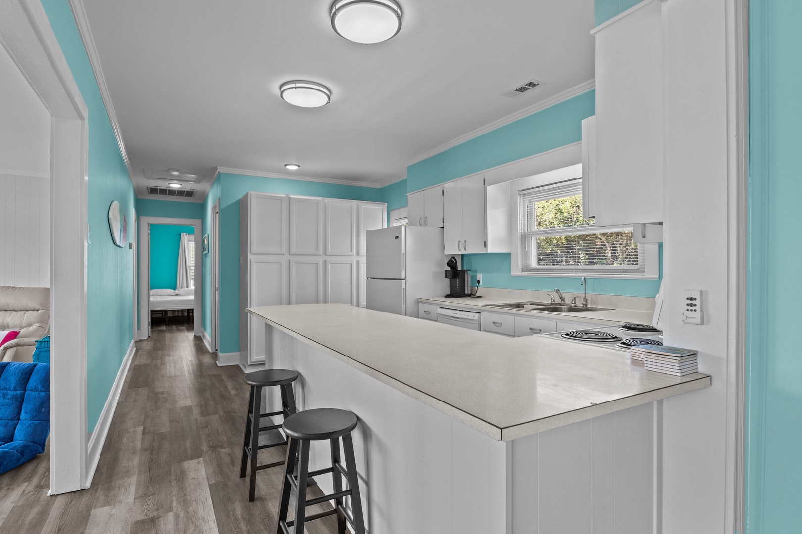 Cook your favorite meals in this bright, modern kitchen featuring cheerful turquoise walls and sleek white cabinets with plenty of storage.