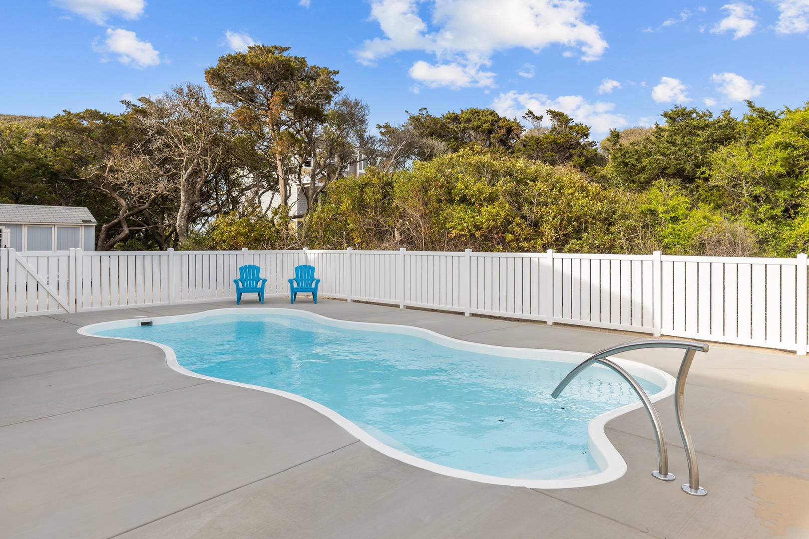 Dive into your private oasis! This sparkling pool awaits with cozy blue chairs for lounging under endless blue skies.
