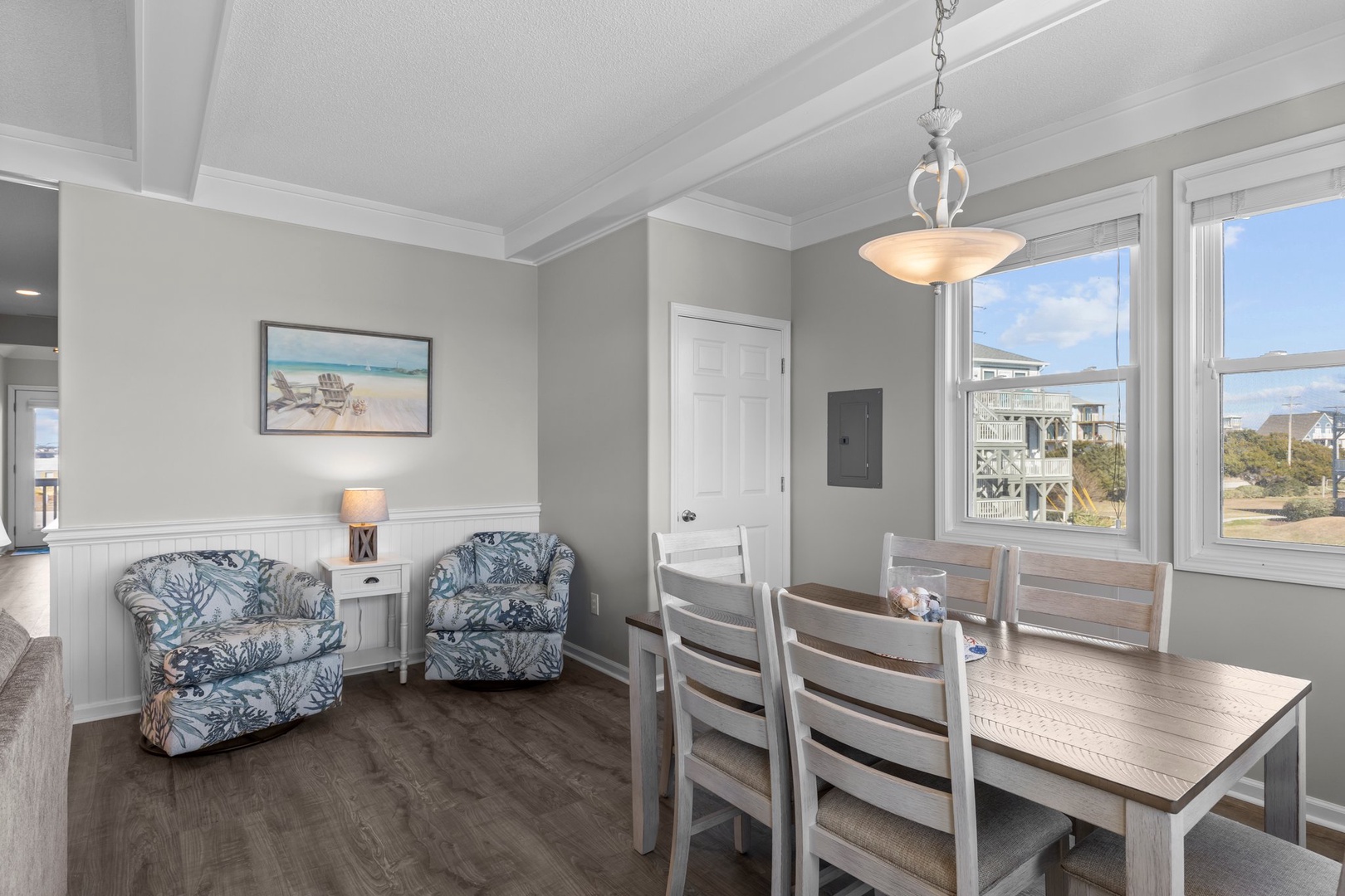 Your bright dining space features coastal charm with elegant furnishings and natural light streaming through large windows.