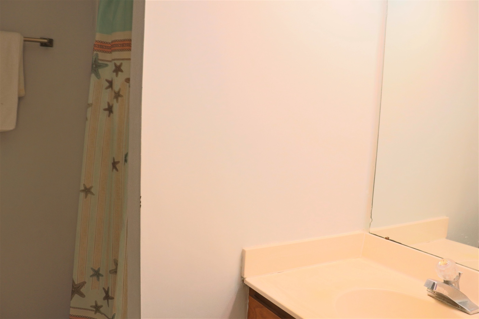 Step into your private bathroom with a stylish star-patterned shower curtain and warm vanity lighting.