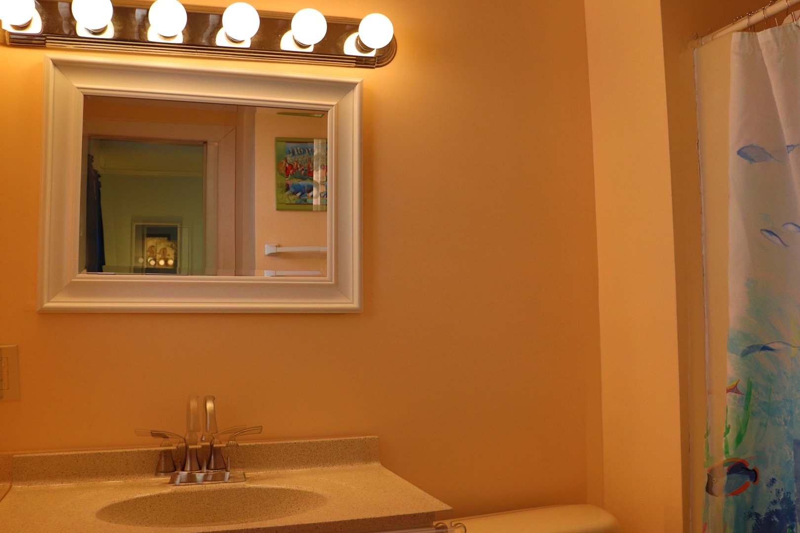 Your bright bathroom features Hollywood-style vanity lighting and warm gold tones, creating a welcoming space for your morning routine.