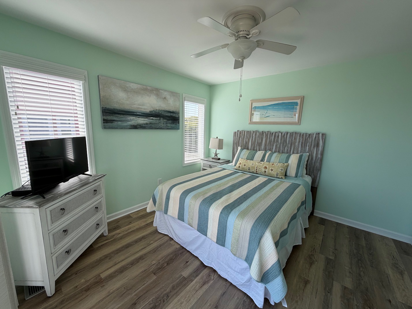 Unwind in your tranquil bedroom with coastal-inspired decor, cooling ceiling fan, and plenty of natural light streaming through the windows.