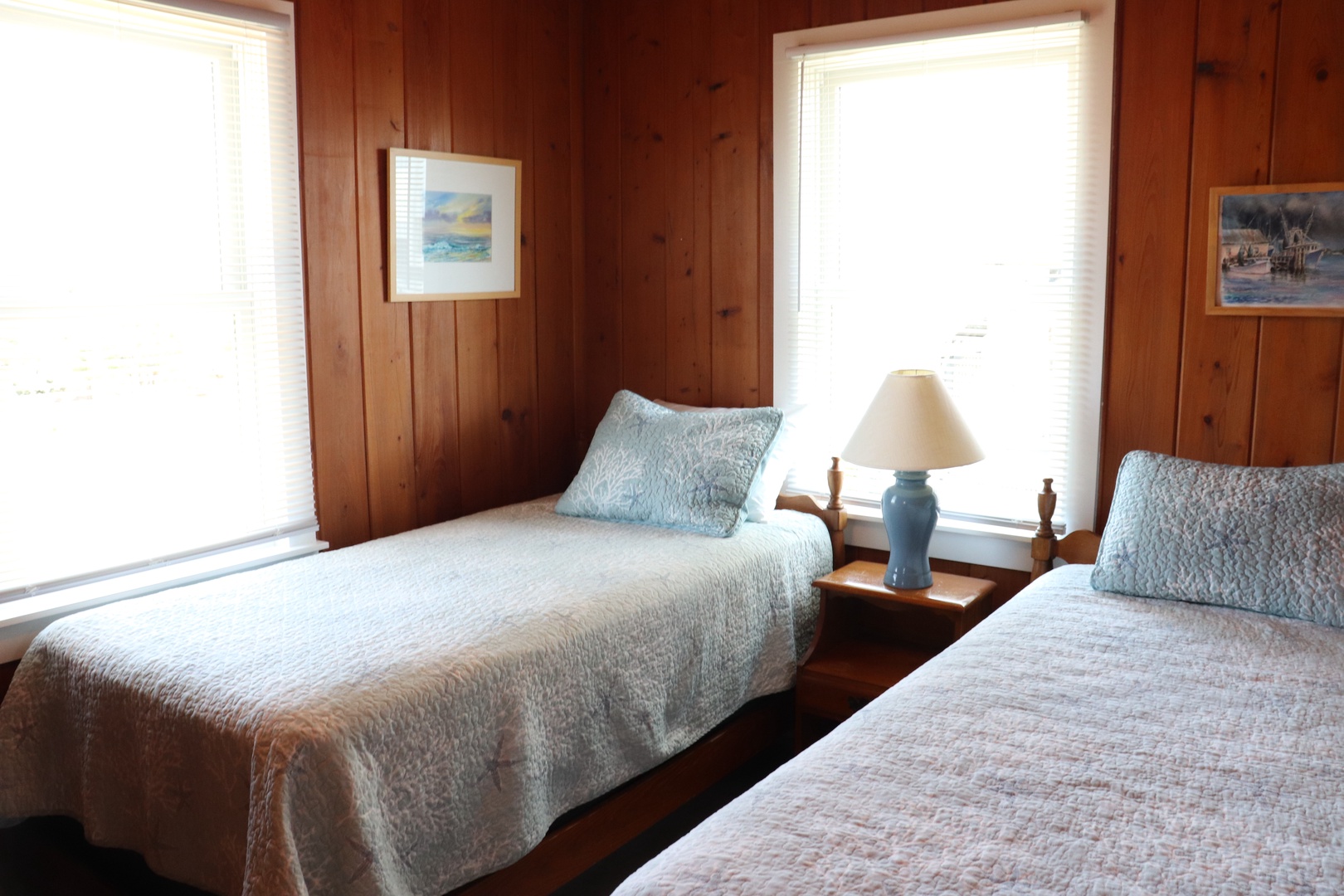 Rest peacefully in your charming twin bedroom, where warm wood paneling and soft quilts create a cozy retreat bathed in natural light.