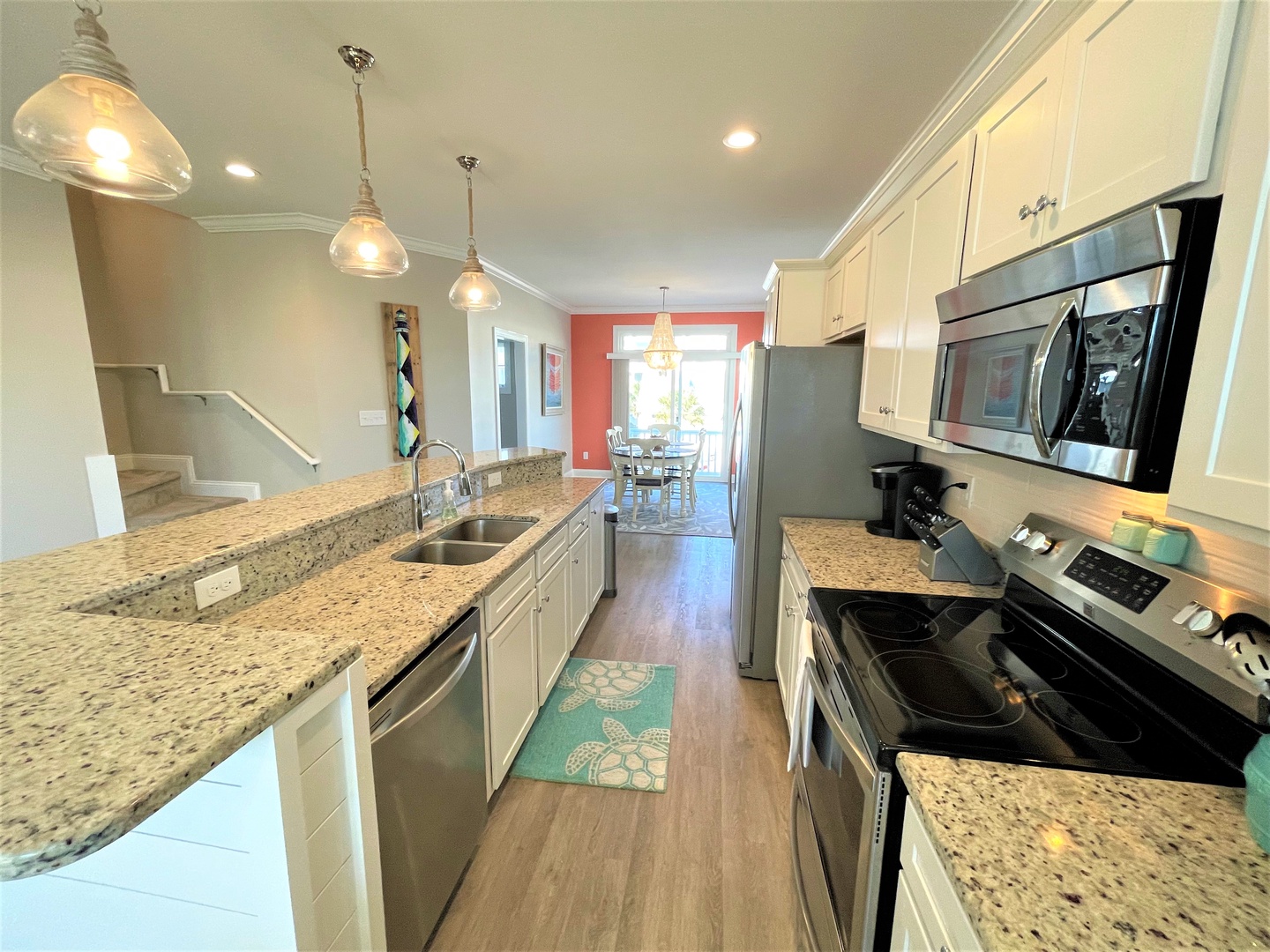 Step into your fully equipped galley kitchen featuring granite countertops, stainless steel appliances, and pendant lighting for inspired home cooking.
