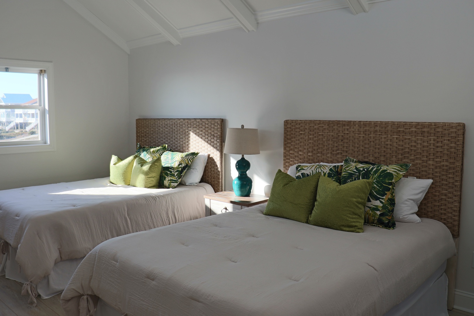 Drift off peacefully in your bright twin bedroom with woven headboards and tropical-inspired pillows creating a coastal sanctuary.