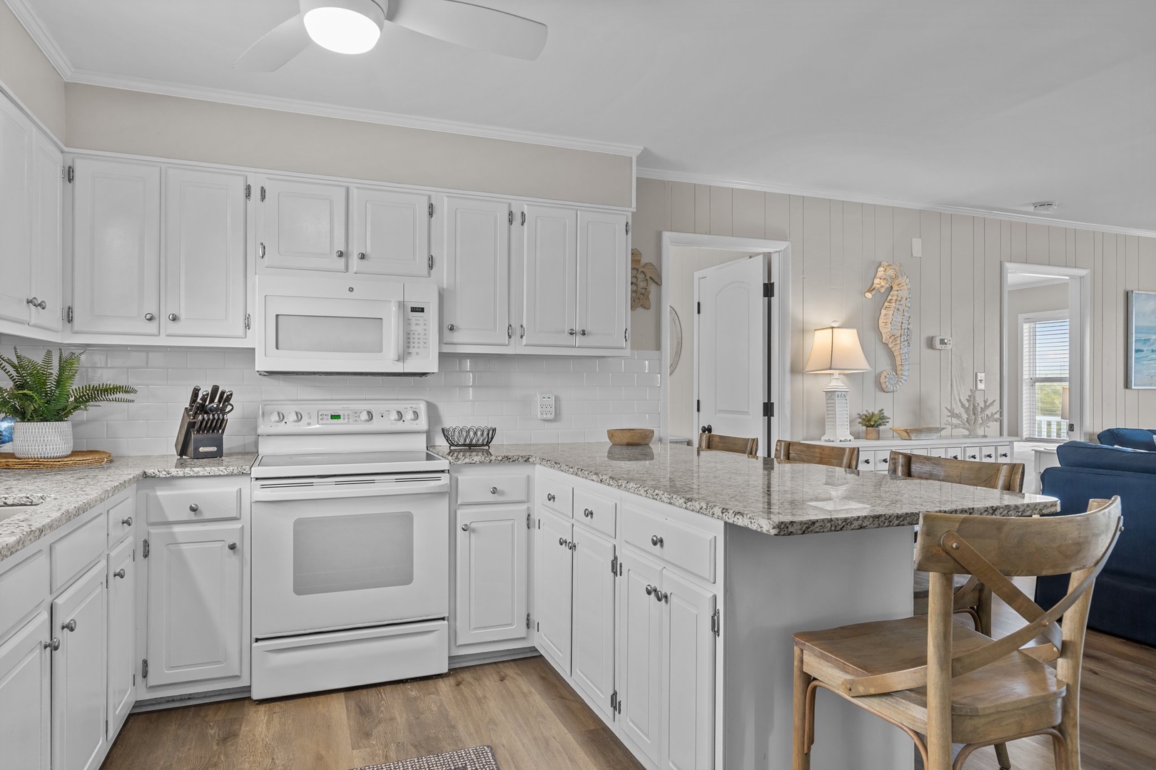Your spacious kitchen awaits with gleaming granite counters, full appliances, and coastal charm—perfect for preparing meals together.