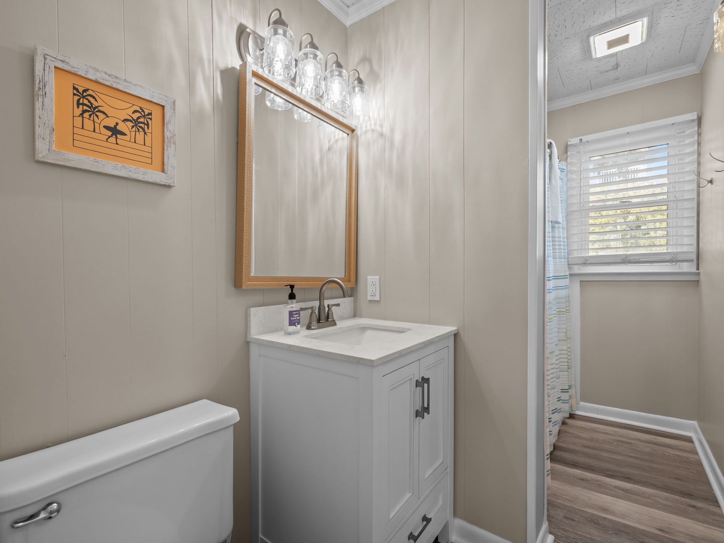 Your private bathroom features elegant lighting, coastal artwork, and modern fixtures for a refreshing morning routine.