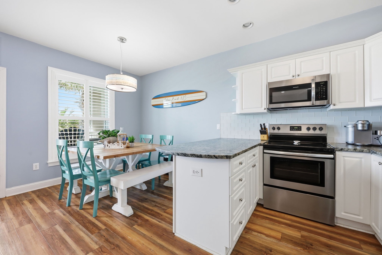 Step into your bright, coastal-inspired kitchen and dining area, where morning coffee meets ocean breezes. Cook your favorite meals with modern appliances and gather at the cheerful turquoise dining table.
