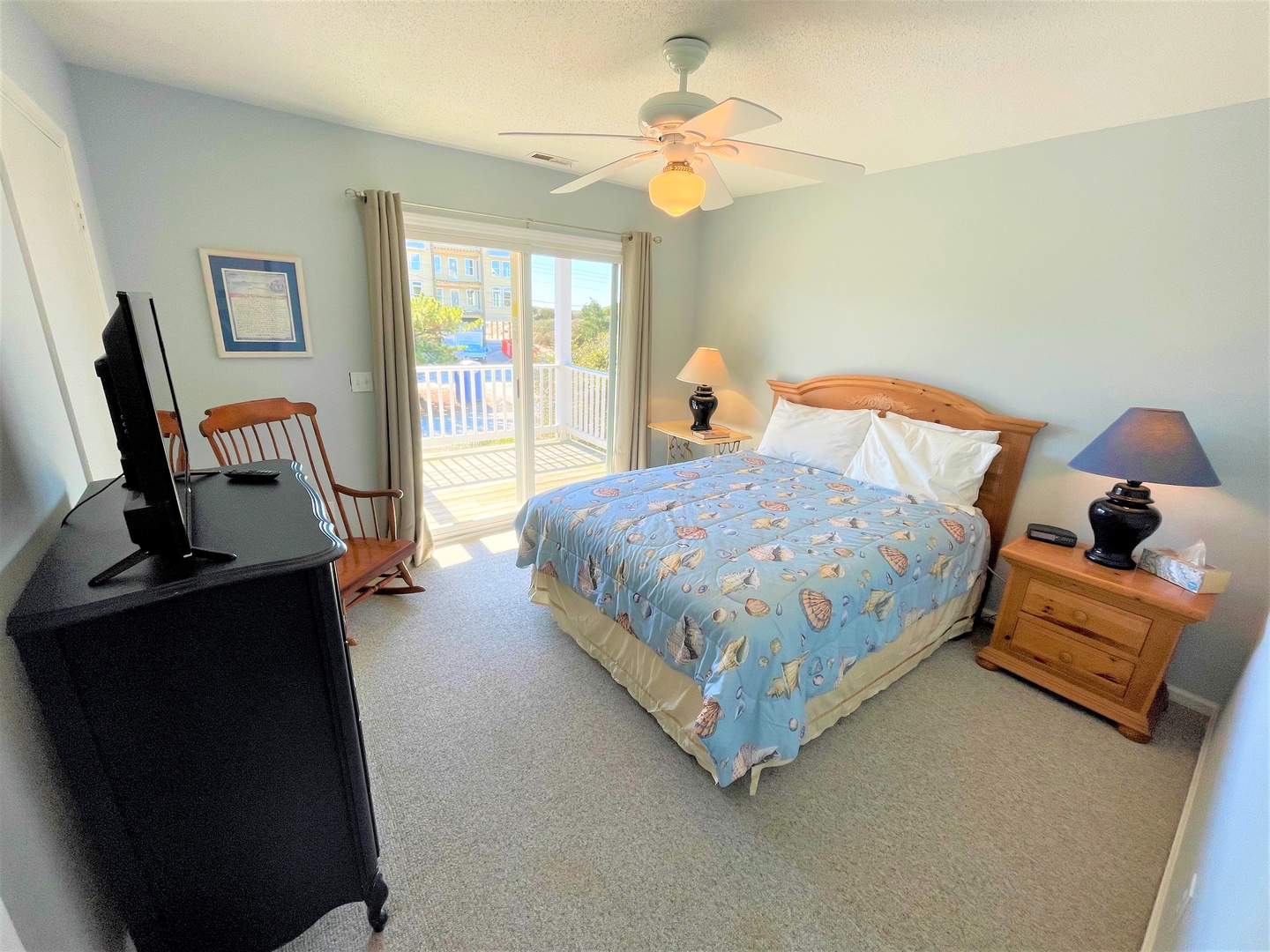 Drift off to sleep in your comfortable bedroom with ocean-themed bedding, gentle ceiling fan, and private balcony access for fresh morning air.