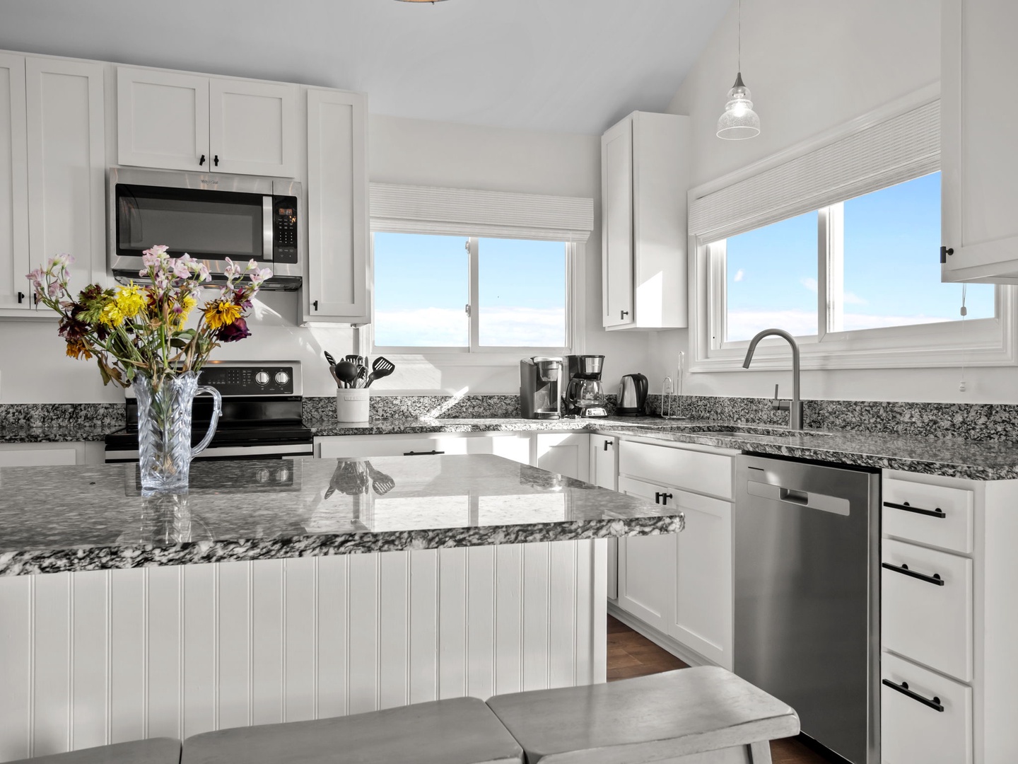Your bright kitchen awaits with granite counters, modern appliances, and beautiful sky views through large windows.