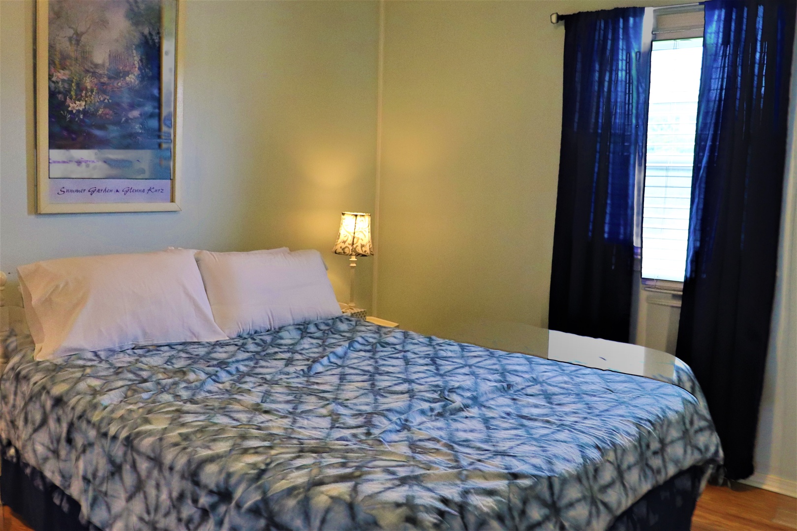 Drift off in your cozy bedroom with soft blue linens, warm bedside lighting, and cheerful blue curtains filtering gentle daylight.