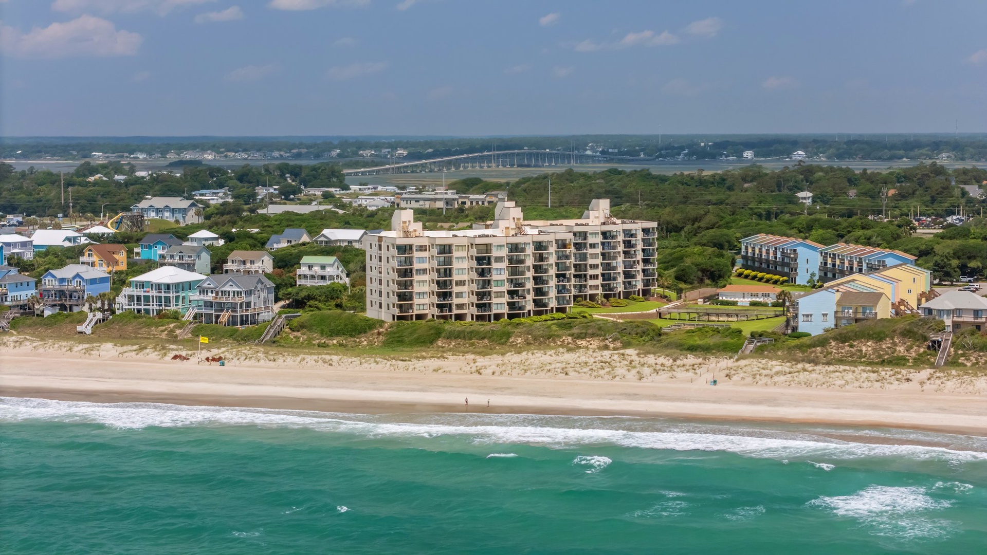 Beachfront property development with direct access to pristine sandy shoreline and emerald waters, surrounded by coastal residential community.