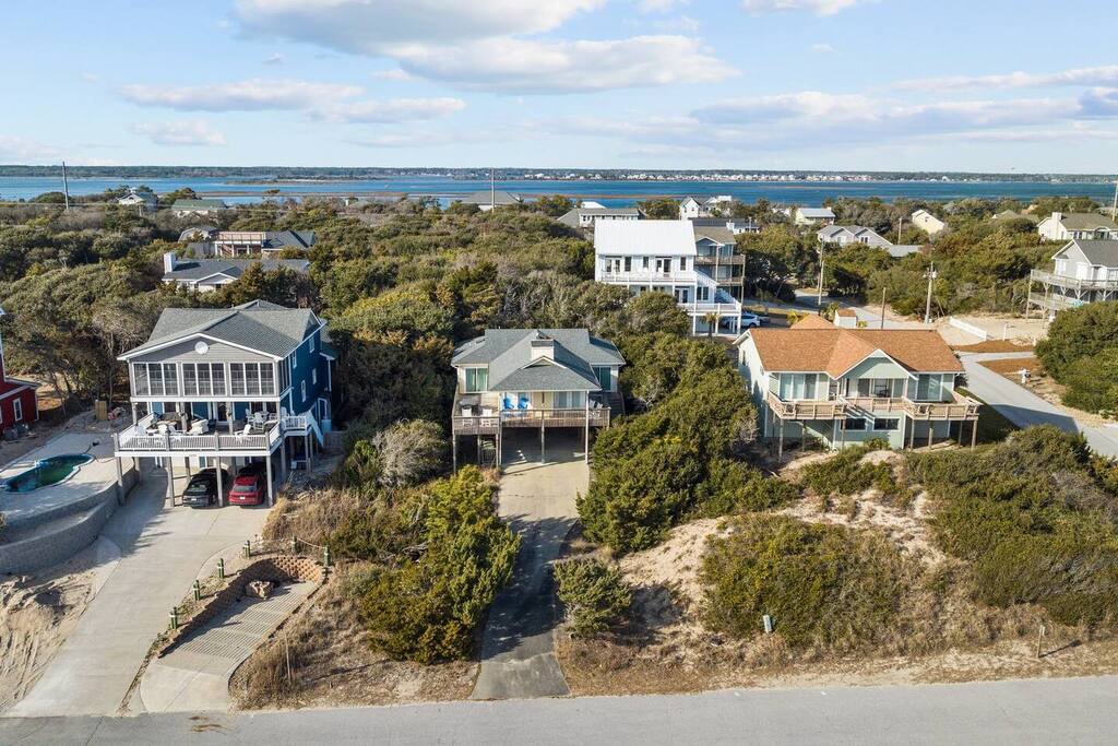 Charming coastal homes nestled among natural dunes, just steps from pristine waterfront with stunning bay views and peaceful neighborhood setting.
