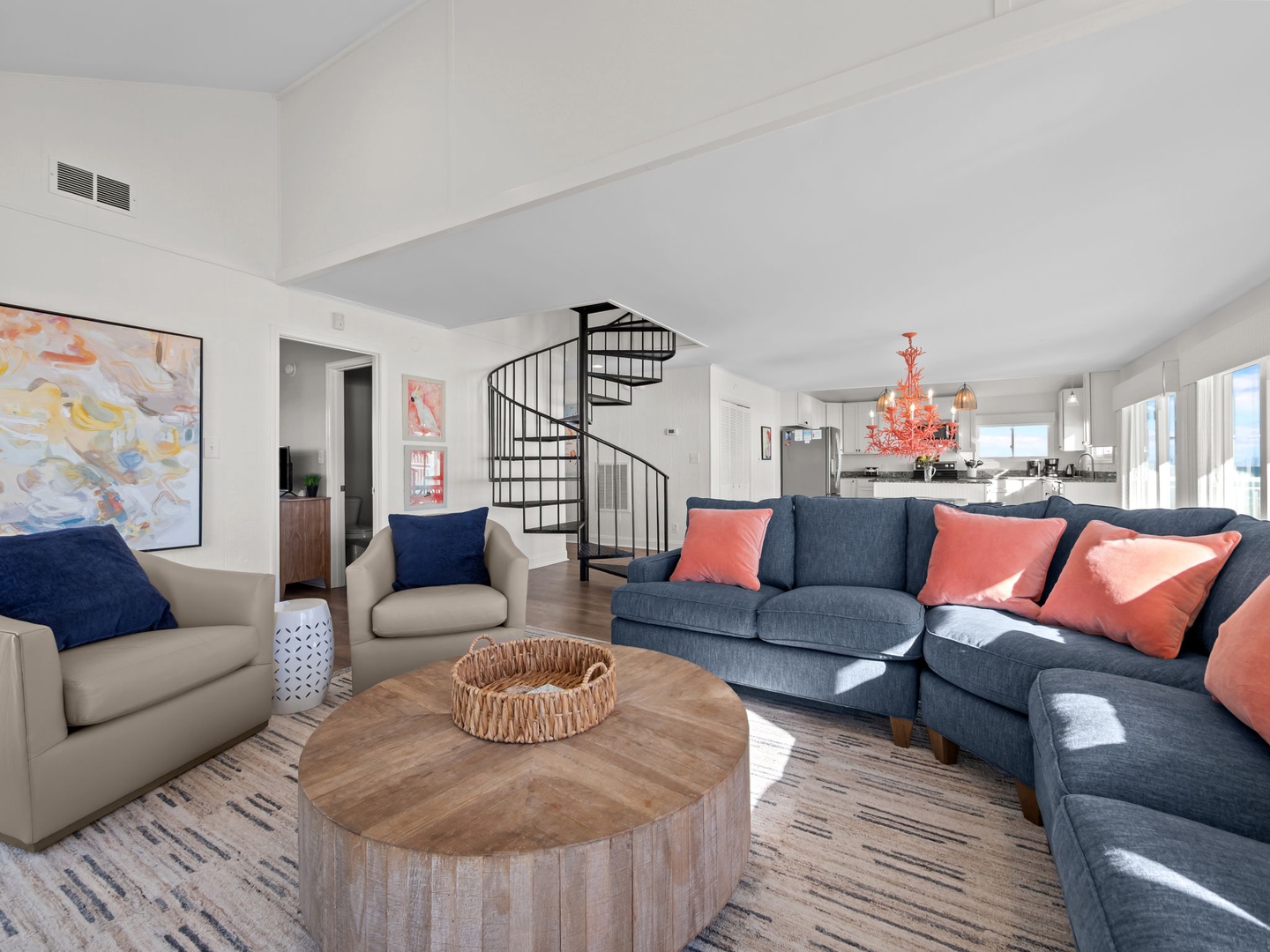 Sink into plush seating with coral accents while natural light floods your stylish retreat through expansive windows.