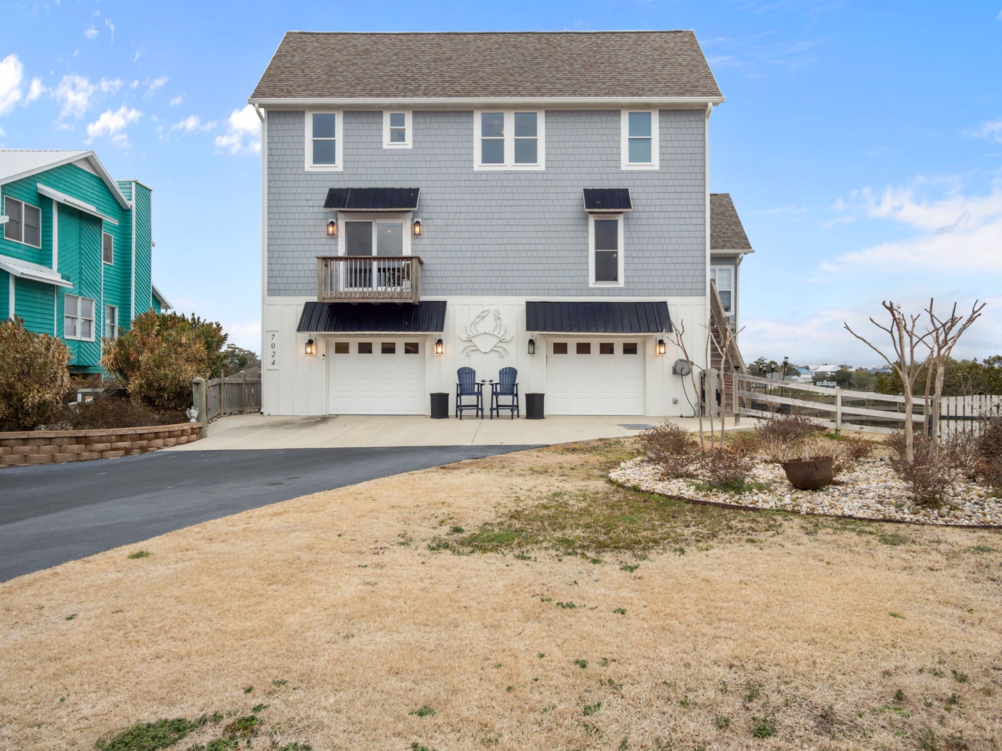 A charming coastal property with twin garage spaces, featuring classic shingle siding and a welcoming balcony overlooking the peaceful neighborhood.